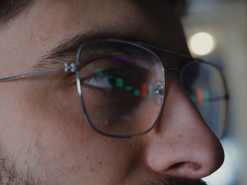 Osoba gleda u laptop, nosi naočare sa kojih se vidi prikaz investicije