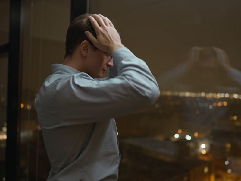 Osoba u stresu se drži za glavu i gleda kroz prozor