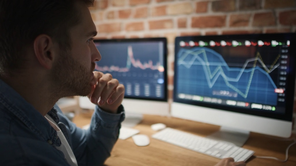 Investitor analizira grafikone i razmatra troškove ulaganja u ETF fondove na dva monitora