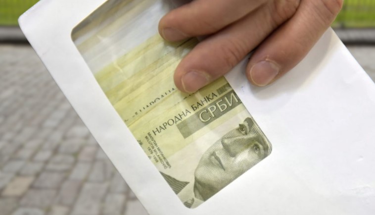 Ruka drži kovertu sa dinarima