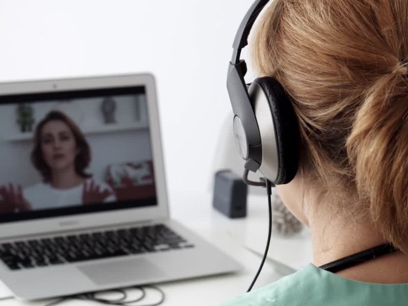 Devojka preko slušalica i laptopa obavlja razgovor online