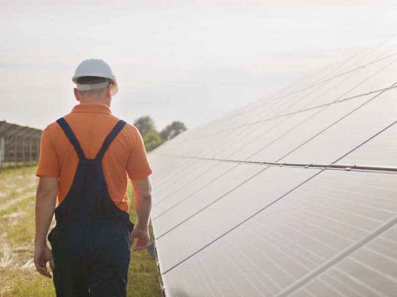 radnik šeta pored postavljenih solarnih panela