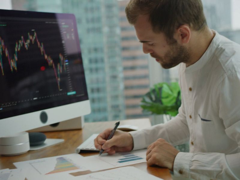 čovek koji se obavi online investiranjem zapisuje nešto na papir