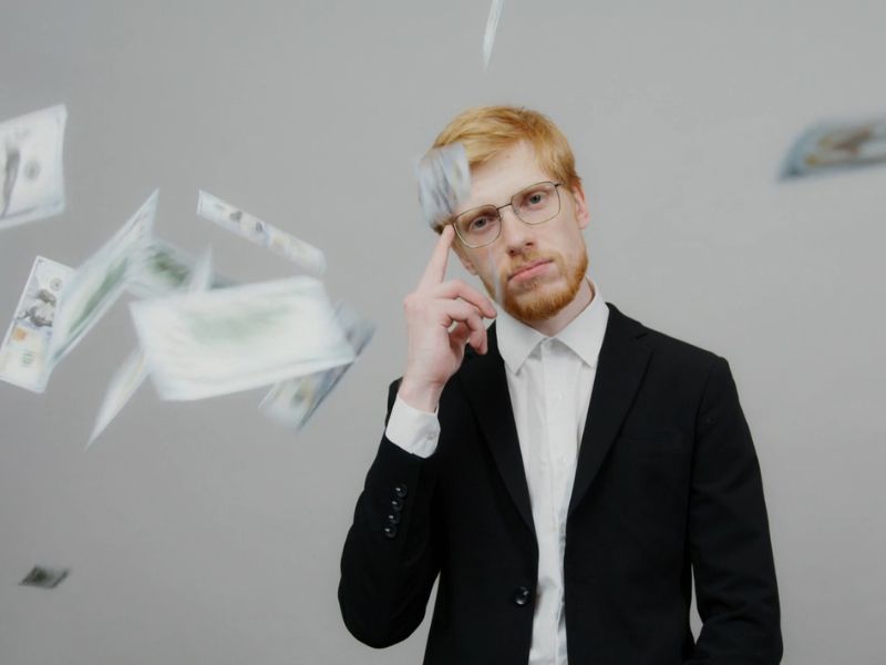 čovek se drži za naočare i glavu simulirajući na pametno investiranje, novac leti oko njega