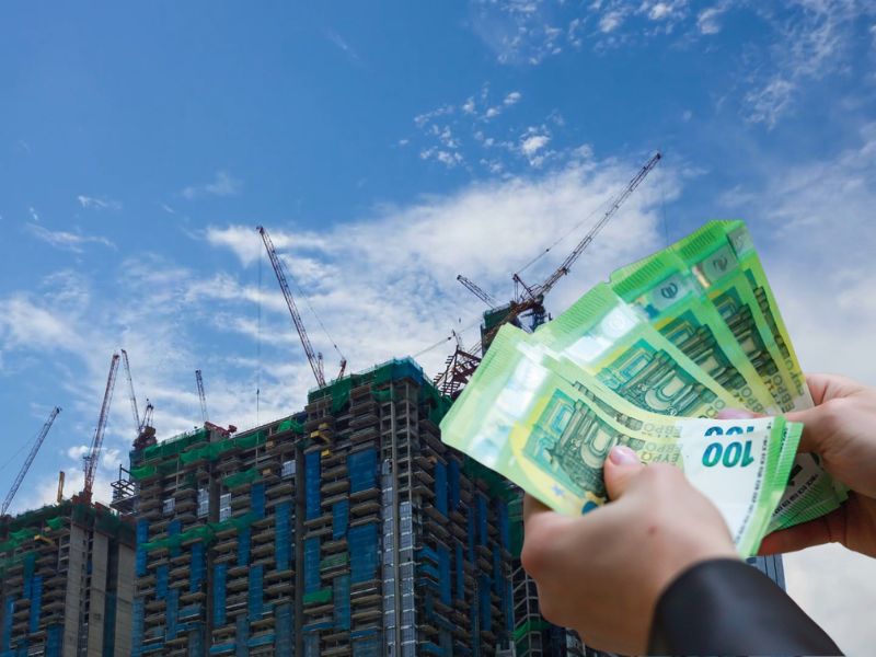 prikaz zgrada u izgradnji i osobe koja drži novac u ruci