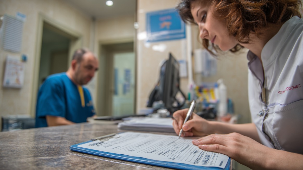 Medicinska radnica popunjava dokumentaciju na recepciji privatne klinike