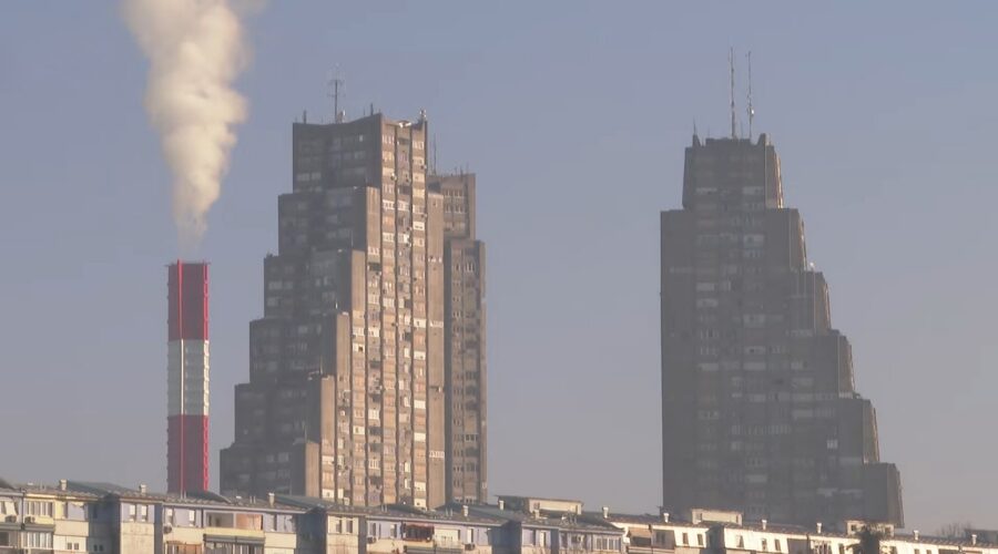 Dimnjak sa crveno-belim prugama ispušta gusti beli dim u nebo pored Geneks kule.