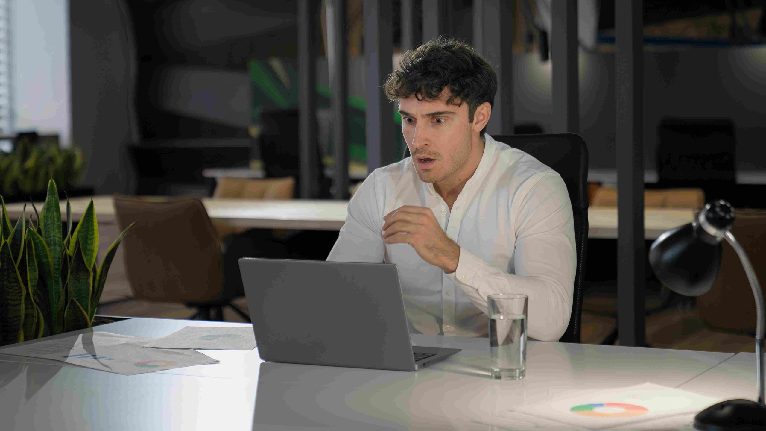 Muškarac iznenađeno gleda u laptop dok analizira poslovne podatke