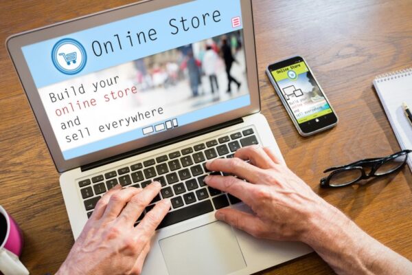 Pokretanje online prodavnice na laptopu uz mobilni telefon, beležnicu i šolju kafe