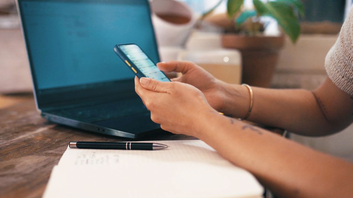 Žena koristi mobilni telefon pored laptopa dok priprema registraciju online prodavnice