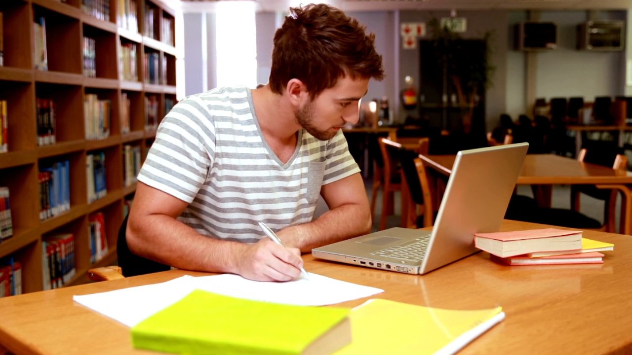 Student popunjava dokumenta za studentski kredit uz laptop u biblioteci