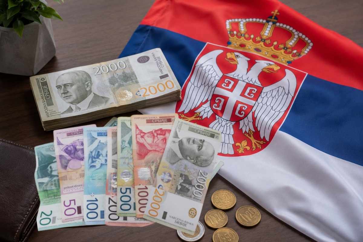 Srpski dinari i zastava Srbije na drvenom stolu.