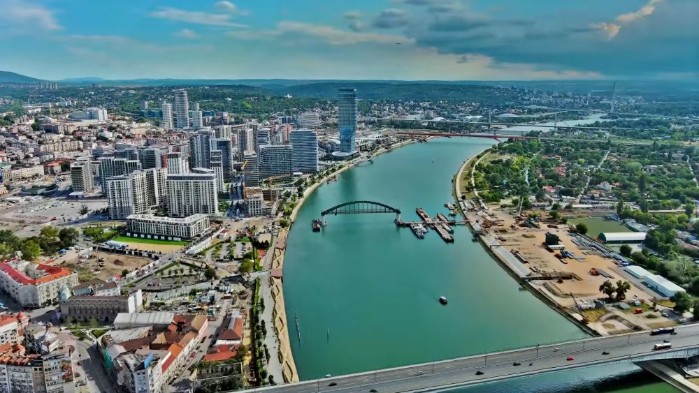 Panoramski pogled na Beograd, Savu, mostove i moderne zgrade uz obalu.