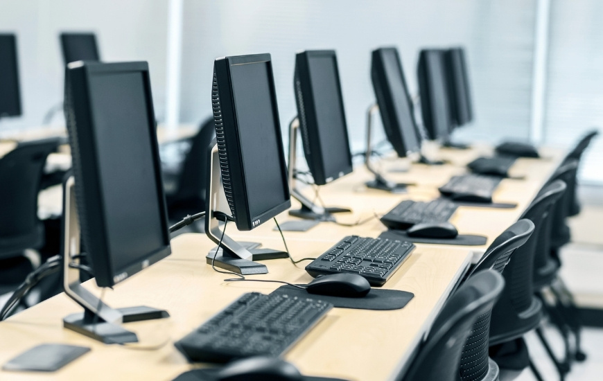 Računarska oprema u kancelariji sa više radnih mesta, monitorima, tastaturama i miševima za svakodnevni poslovni rad.
